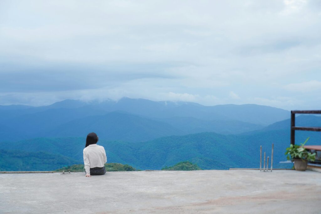 pexels-photo-32506013-32506013 Woman sitting alone, contemplating the expansive mountain landscape for a serene moment.